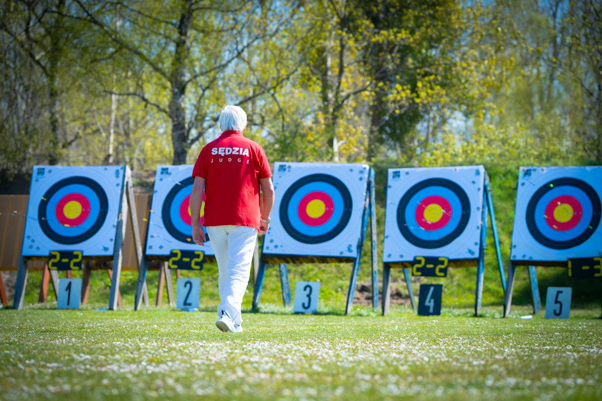 Is Archery a Sport? Common Myths About Archery, Explained 1 Archer walking toward targets on a sunny outdoor range.